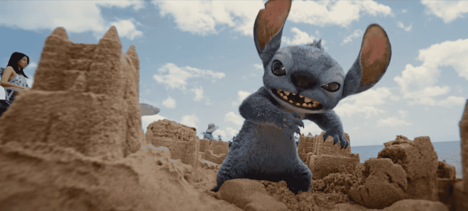 animated film still of Stitch charging through sand castles on the beach