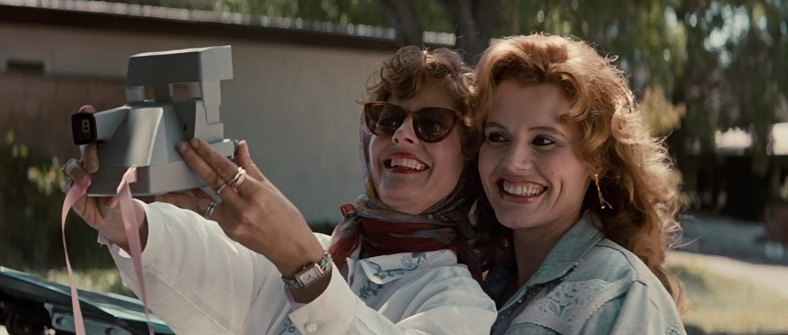Film still from Thelma & Louise (1991) showing two women taking a photograph of themselves with a polaroid camera