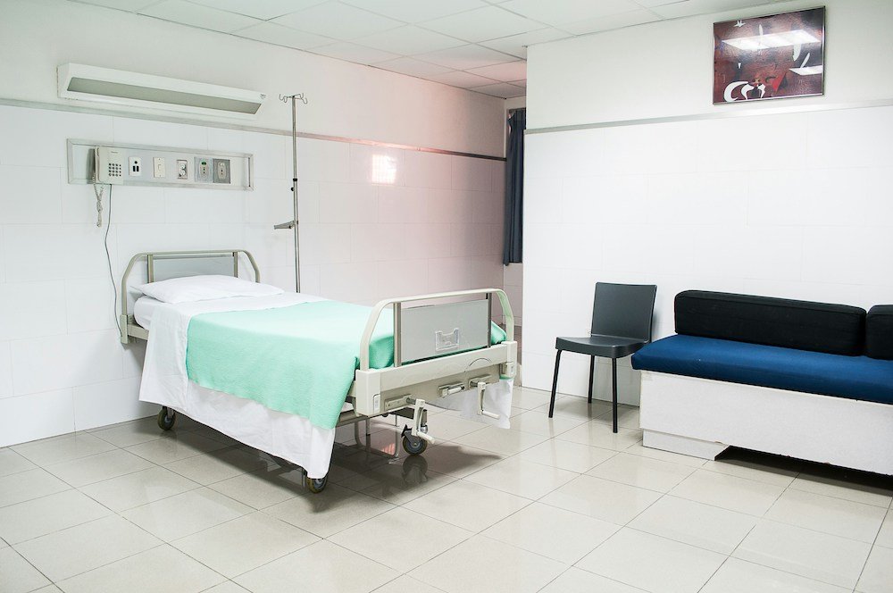 image of a simple hospital room with a hospital bed and chair