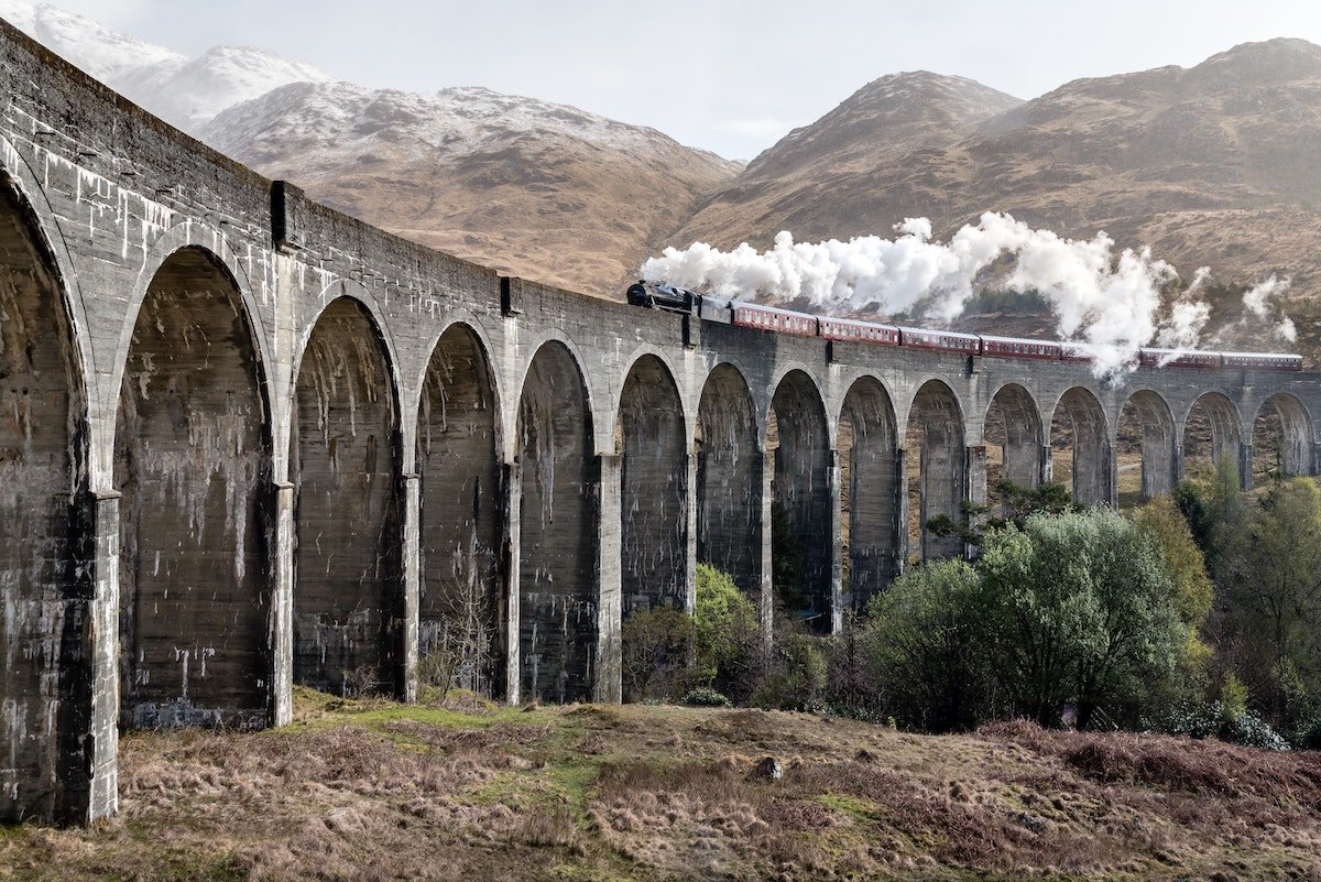 Glenfinnan Viaduct in the Scottish Highlands with steam train crossing – iconic filming location for Harry Potter and other productions