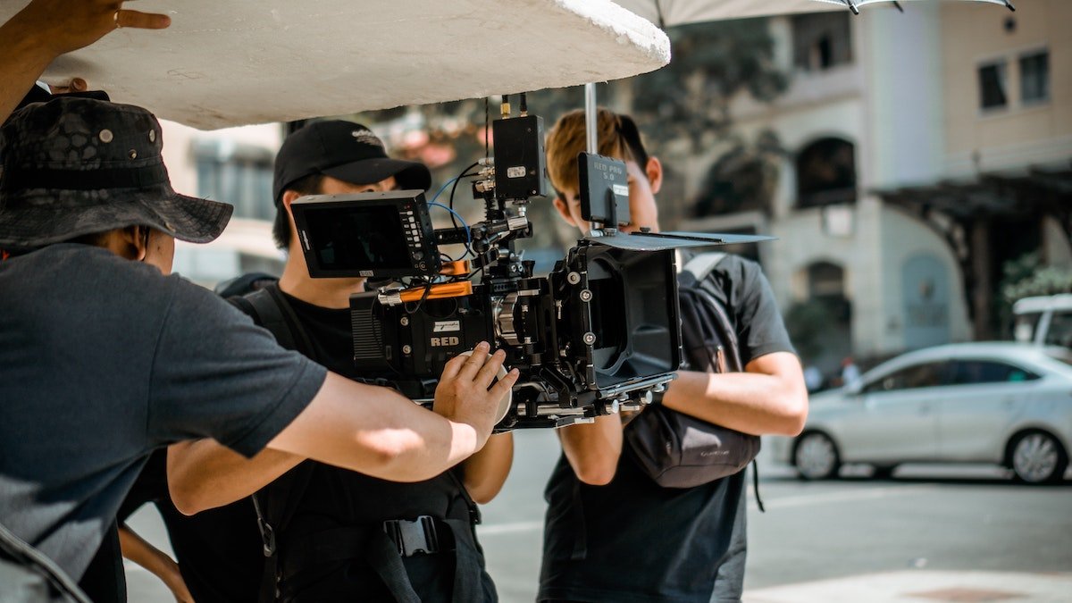 Film crew operating a RED camera rig on a city street, shooting an outdoor production at a public filming location