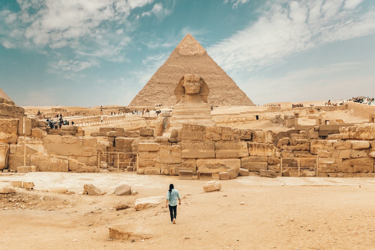 Tourist walking toward the Great Sphinx and Pyramid of Khafre at Giza, Egypt – a world-famous filming and scouting location