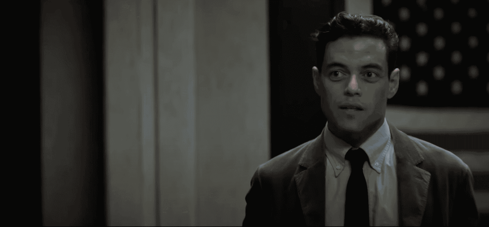 film still from The Amateur showing Rami Malik in front of an American flag