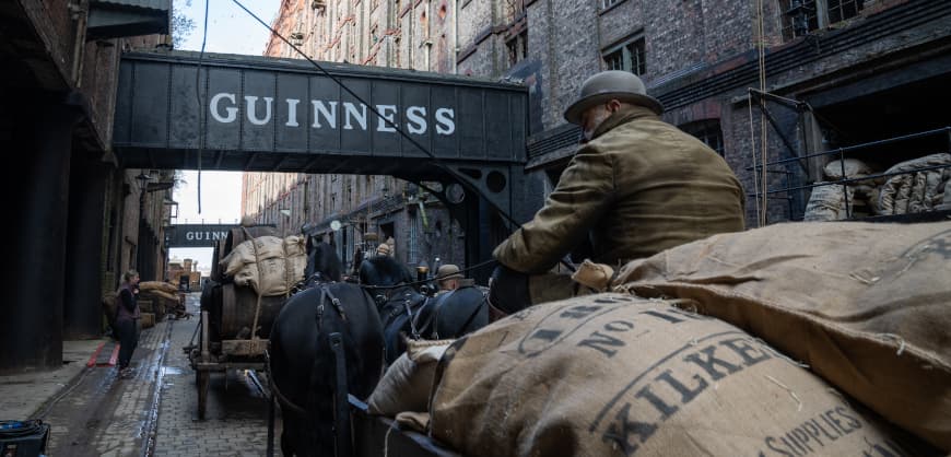 Film still from House of Guiness showing a character on a horse-drawn carriage in the streets